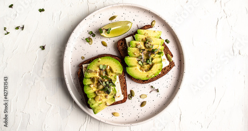 Healthy avocado toasts for breakfast or lunch with rye bread, sliced avocado, cheese, pumpkin and sesame seeds. banner, catering menu recipe top view