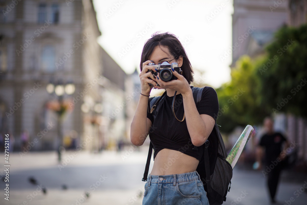 Tourist woman in the city.  Young woman taking photo in the city with camera.