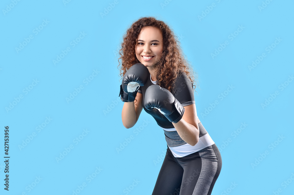 Beautiful young woman in boxing gloves on color background Beautiful young woman in boxing gloves on color background