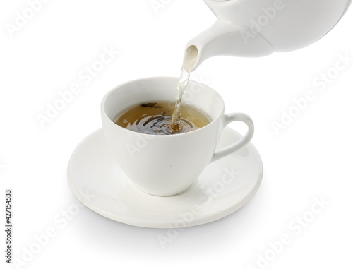 Pouring of green tea from teapot into cup on white background