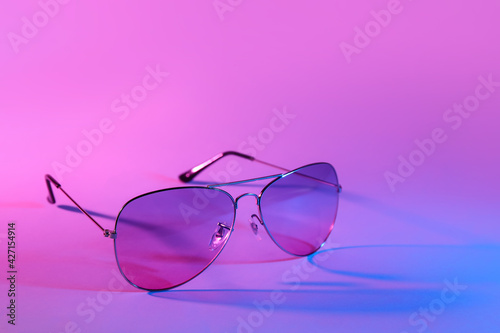 Stylish sunglasses on color background