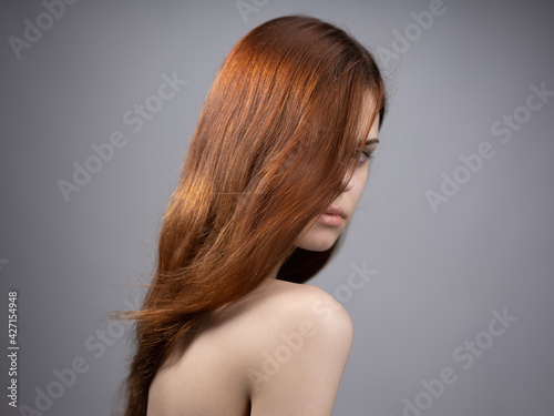 fashionable woman with red hair naked shoulders side view