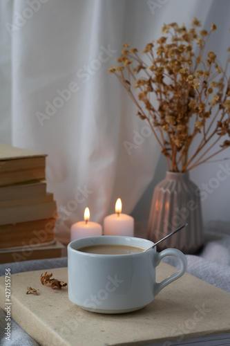A cup of coffee  books  a bouquet of flowers and candles on the table. Composition in brown-beige tones. Stylish still life  blog life concept.