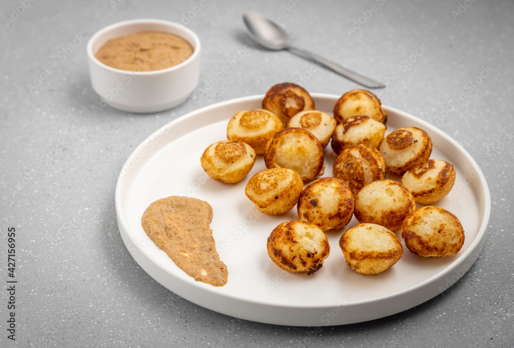 Suji appe or appam served on a appam pan with peanuts and tamarind chutney