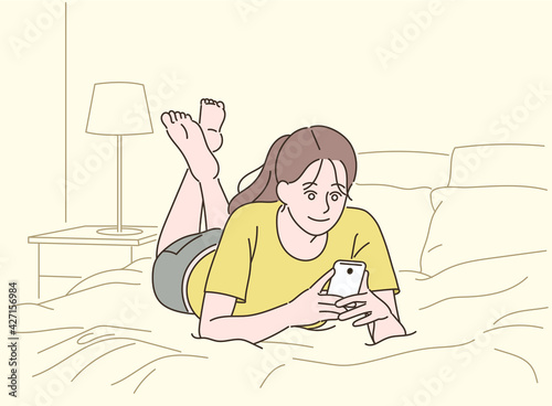 A girl lying comfortably on her bed and looking at her cell phone. hand drawn style vector design illustrations. 