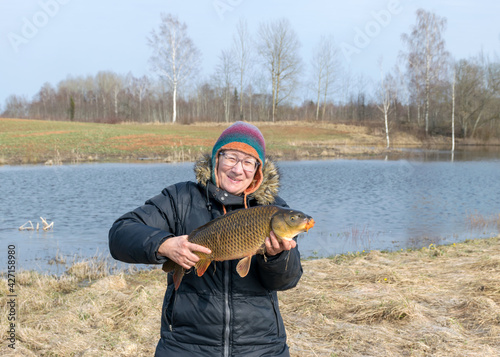 a happy fisherman on the lake shore, caught carp in a woman's hand, amateur carp fishing, fishing as a hobby