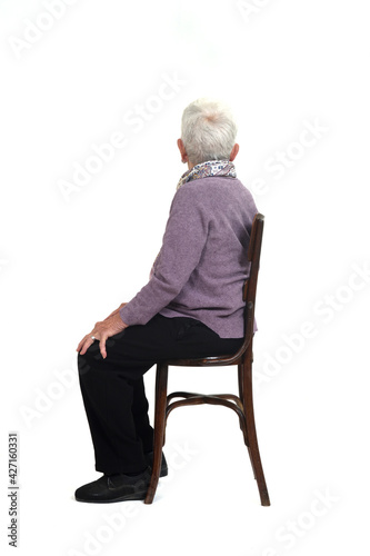 side view of a senir woman sitting on chair looking away on white background photo