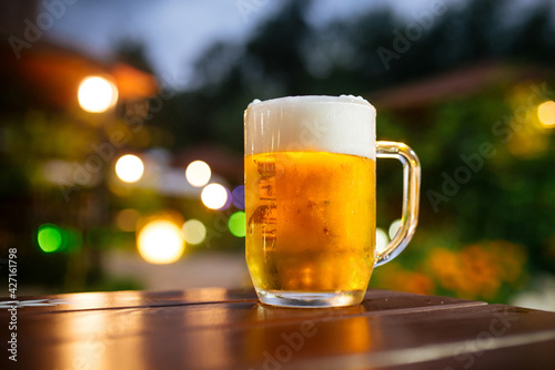 Glass mug of fresh cold beer on the table in summer terrace