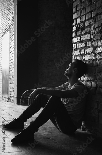 Side view of handsome young man sitting and posing on street classic black and white photo. Monochrome image