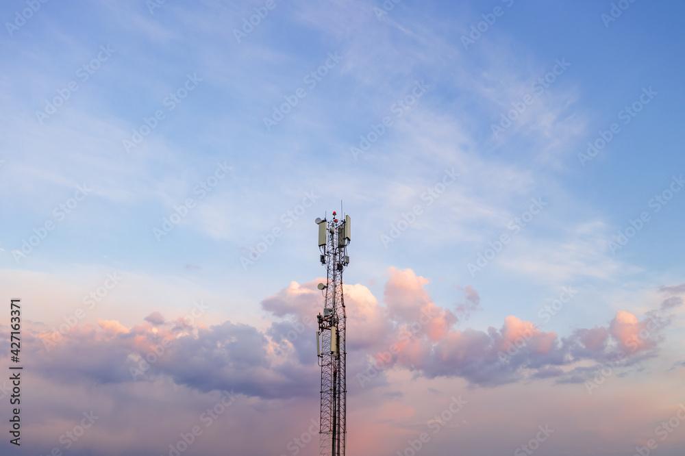 A cell phone tower rises against a twilight sky, a telecommunications tower A cell phone tower rises against a twilight sky, a telecommunications tower
