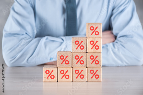 Businessman hand takes a wooden cube block depicting,shown the percentage symbol icon. Interest rate financial and mortgage rates concept.