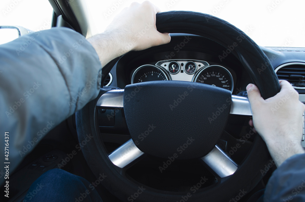 The driver's hands are on the steering wheel. Man sitting and driving in the car The driver's hands are on the steering wheel. Man sitting and driving in the car