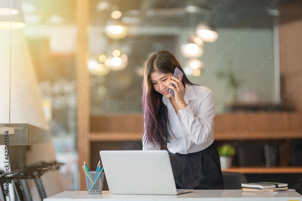 Portrait of businesswoman talking on the phone while working at a worktable in an office room. Portrait of businesswoman talking on the phone while working at a worktable in an office room.