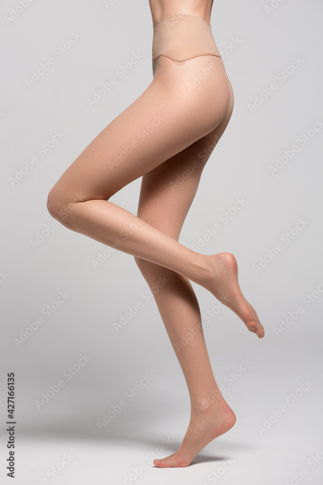 Beautiful long female legs in tights. Gray background. Beautiful long female legs in tights. Gray background.