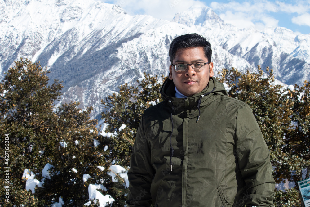 Stylish male hiker standing in front of snowcapped Himalayan mountain