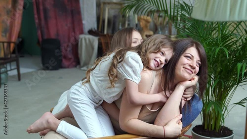 Mom lies on the couch and cuddles with her daughters. happy family. backstage. photo