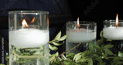 Beautiful well lit table décor with white floating candles and floral plant decoration at a wedding.  photo