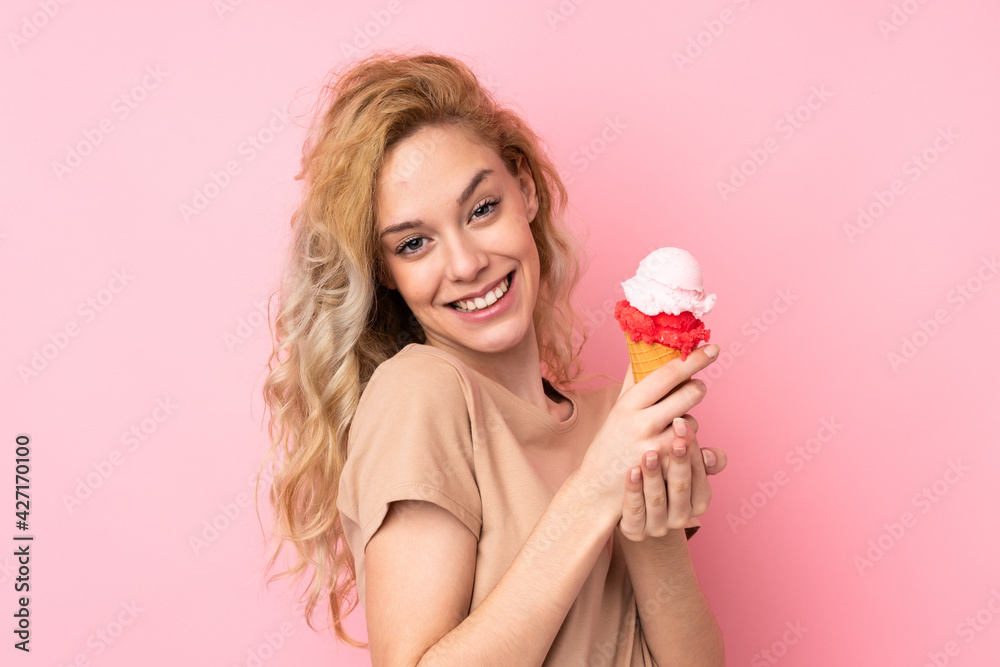 Young blonde woman holding a cornet ice cream isolated on pink background Young blonde woman holding a cornet ice cream isolated on pink background
