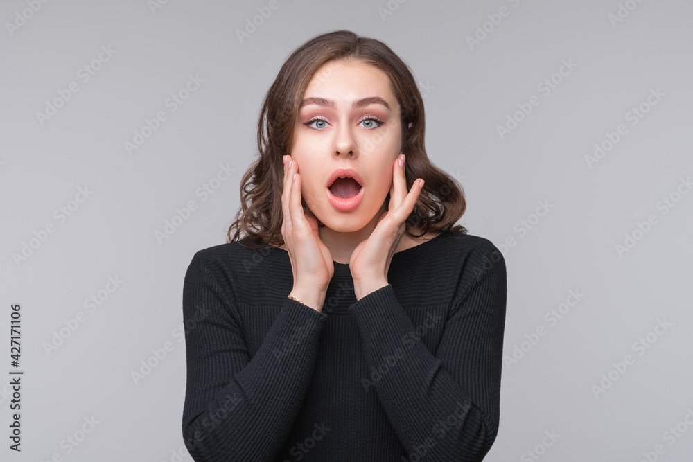 Portrait of shocked afraid woman looking with having wide open mouth gesturing palms, standing gray background Portrait of shocked afraid woman looking with having wide open mouth gesturing palms, standing gray background