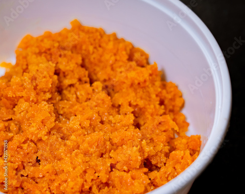Close up of Carrot Halwa or Gajar ka halwa in a white takeout box on a black background.