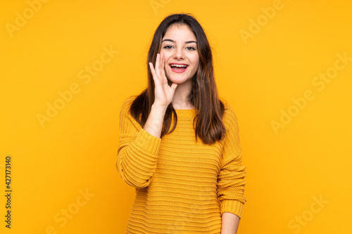Young caucasian woman isolated on yellow background shouting with mouth wide open