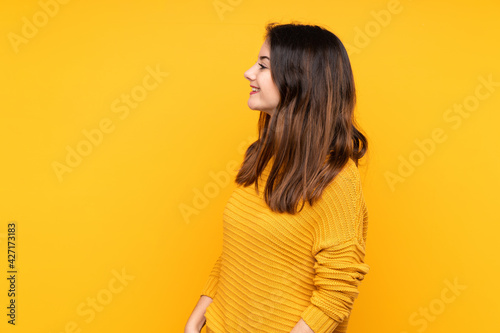 Young caucasian woman isolated on yellow background laughing in lateral position © luismolinero