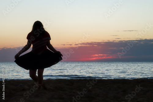 Valokuva Silhouette of a teenage girl doing a curtsy on a beach at sunset at Golden Bay, Malta