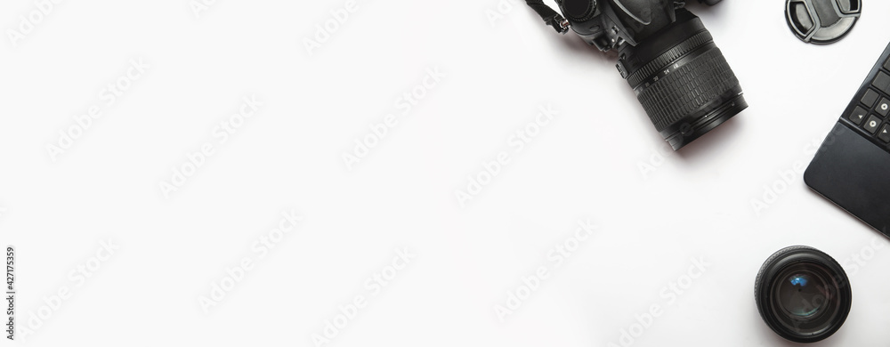 top view of modern photo camera, lenses and equipment over white table background top view of modern photo camera, lenses and equipment over white table background
