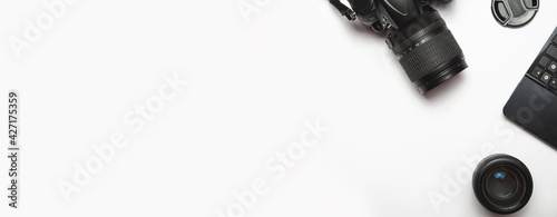 top view of modern photo camera, lenses and equipment over white table background