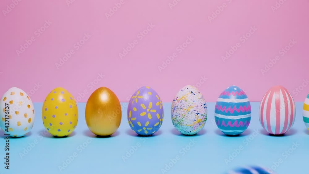 Video of Happy Easter. Colorful painted Easter eggs roll and knock each other on a blue and pink background. Hello spring and easter concept. 4k video. Video of Happy Easter. Colorful painted Easter eggs roll and knock each other on a blue and pink background. Hello spring and easter concept. 4k video.
