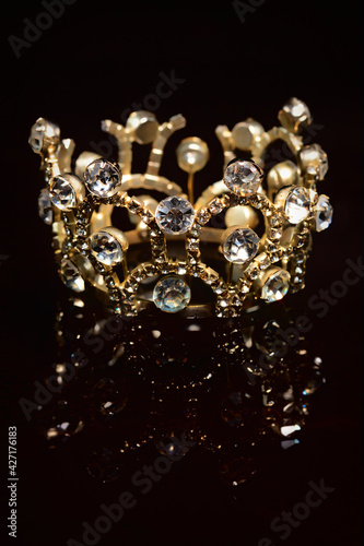 Gold crown with shiny stones on a black background.