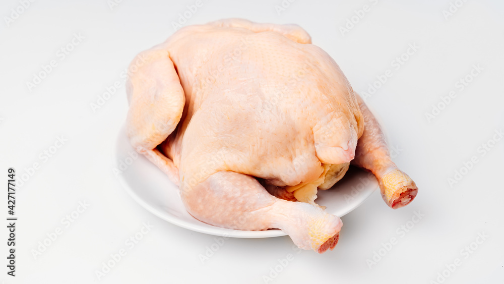 carcass of raw chicken on a white plate on a white background. 