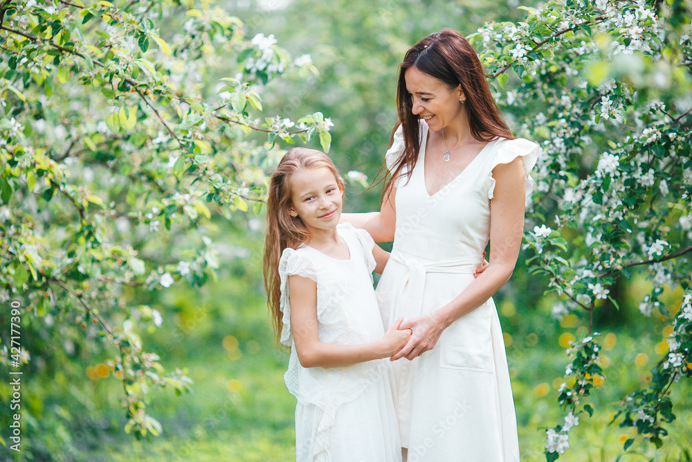 Adorable little girl with young mother in blooming cherry garden on beautiful spring day Adorable little girl with young mother in blooming cherry garden on beautiful spring day
