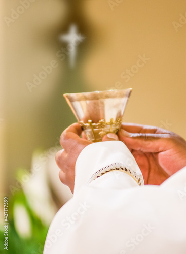 hands of the priest raise the blood of Christ