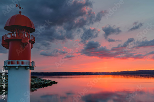 The red pier light at the entrance to the marina by sunset. Right side red pier light by Fahrensodde,  Flensburg, Germany. photo