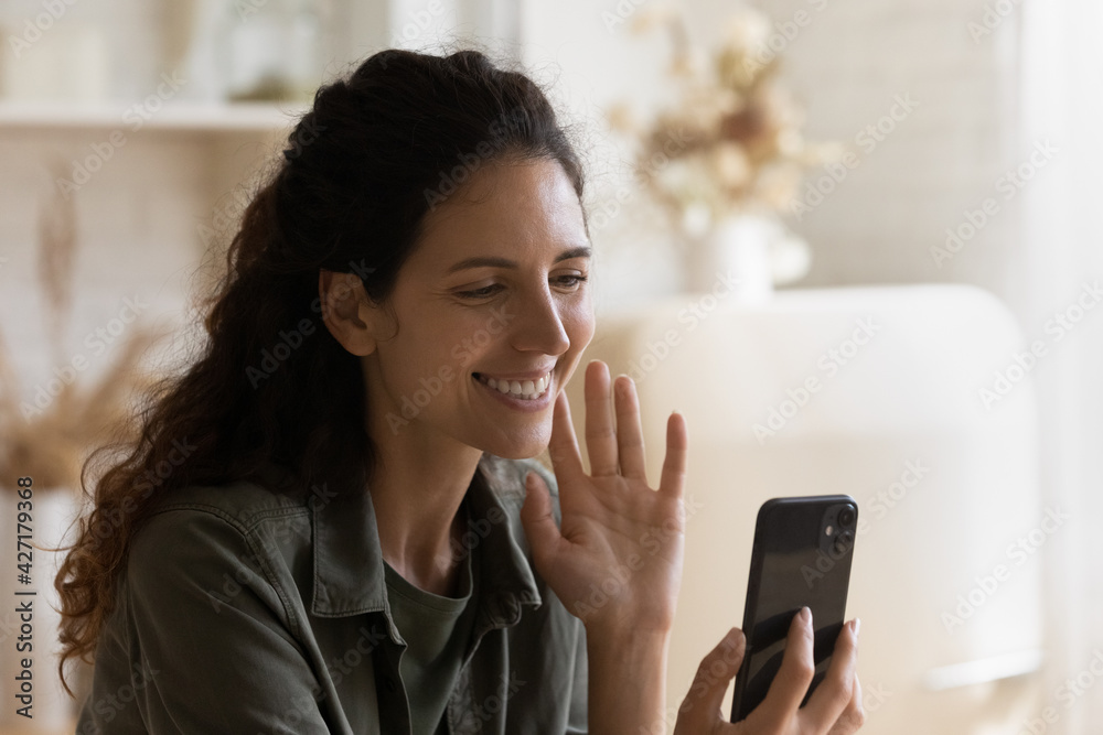 Close up smiling woman waving hand at smartphone, making video call to friends or relatives, chatting online, happy young female blogger greeting, recording vlog for social network, using webcam Close up smiling woman waving hand at smartphone, making video call to friends or relatives, chatting online, happy young female blogger greeting, recording vlog for social network, using webcam