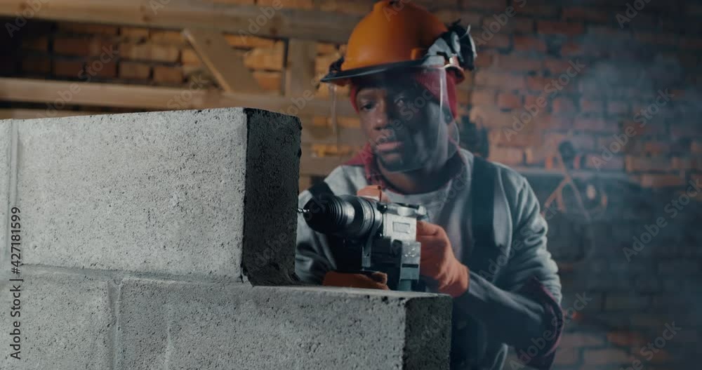 Serious black man drilling concrete block