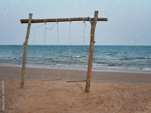 Wooden swing set up on a serene sandy beach.