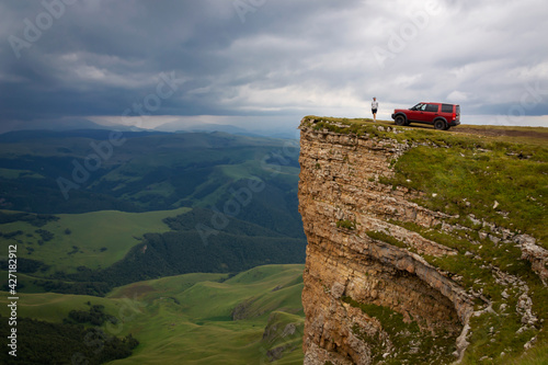 A man and a car on the edge of a cliff. the Bermamyt Plateau. Russia.