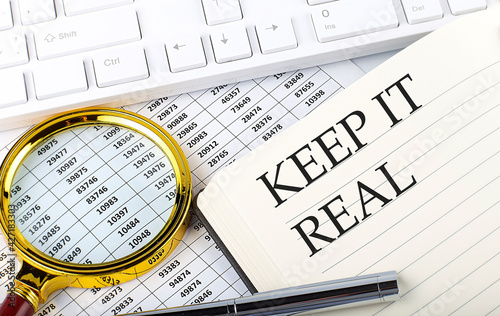 KEEP IT REAL text on notebook with chart  magnifier keyboard and pen   finance and investment concept