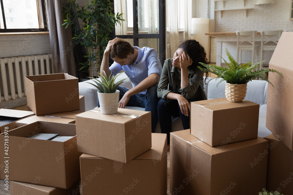 Unhappy frustrated couple sitting on couch with cardboard boxes, eviction, family having problem with dwelling, money or mortgage, worried woman and man lost home, bankruptcy or debt concept Unhappy frustrated couple sitting on couch with cardboard boxes, eviction, family having problem with dwelling, money or mortgage, worried woman and man lost home, bankruptcy or debt concept