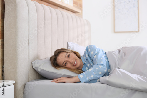 Young woman lying in comfortable bed with silky linens