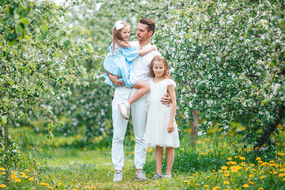 Adorable family in blooming cherry garden on beautiful spring day