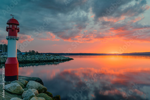 Fototapeta Naklejka Na Ścianę i Meble -  The red pier light at the entrance to the marina of Fahrensodde on the Baltic sea coast  by sunset, Flensburg, Germany 