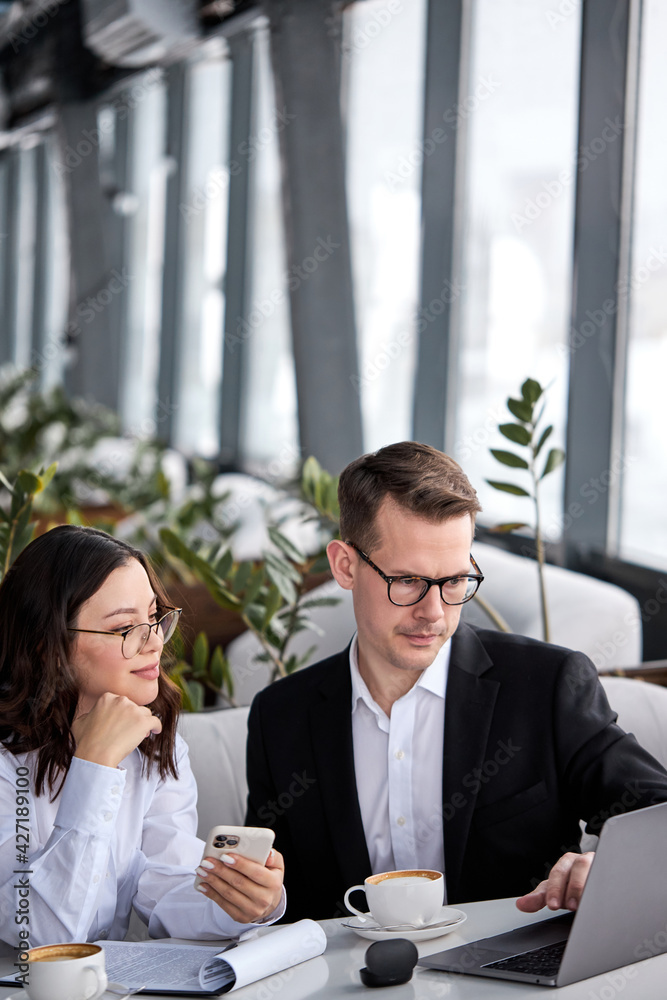 Portrait of business people, man and woman in formal wear sitting in restaurant during working process Portrait of business people, man and woman in formal wear sitting in restaurant during working process