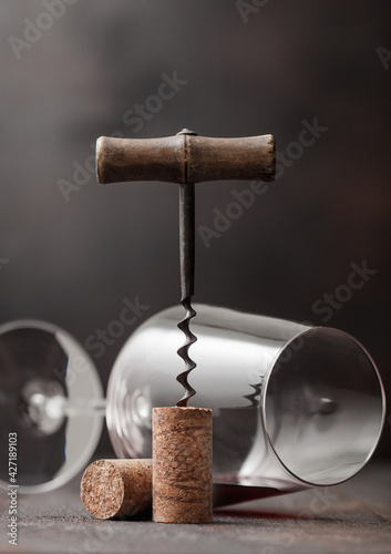 Wine cork with vintage corkscrew on top on wood background with wine glass