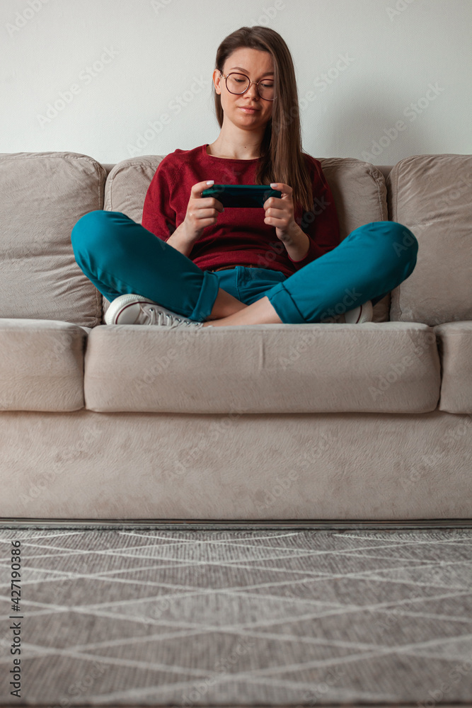Obraz premium Woman using mobile phone, holding in hands sitting on sofa
