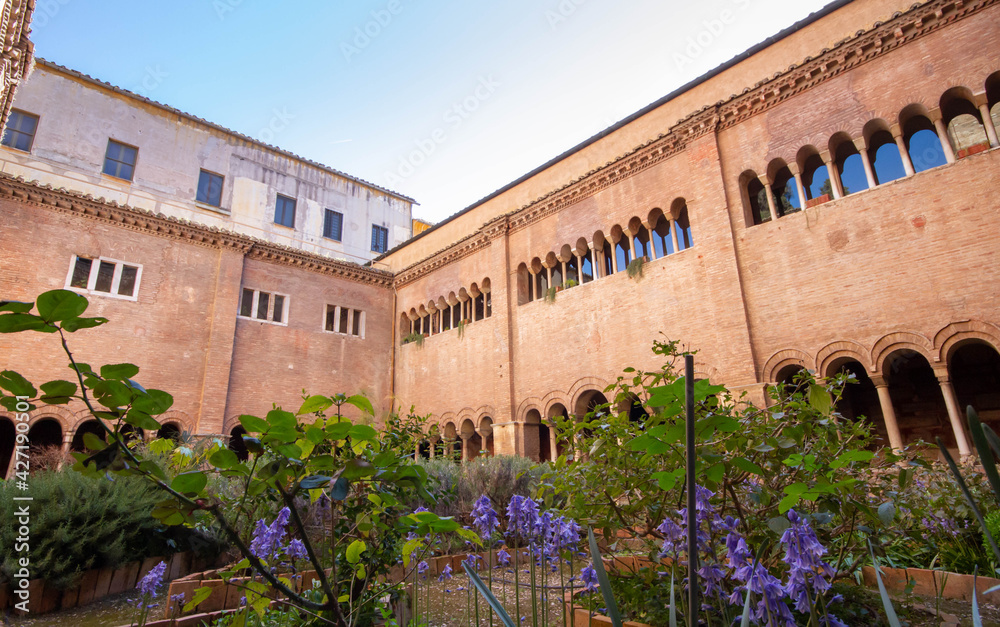 Obraz premium The Cloister of the Basilica of San Lorenzo, with long corridor built in the 12th c.,has three and four light windows, that can be seen on the upper floor overlook the garden