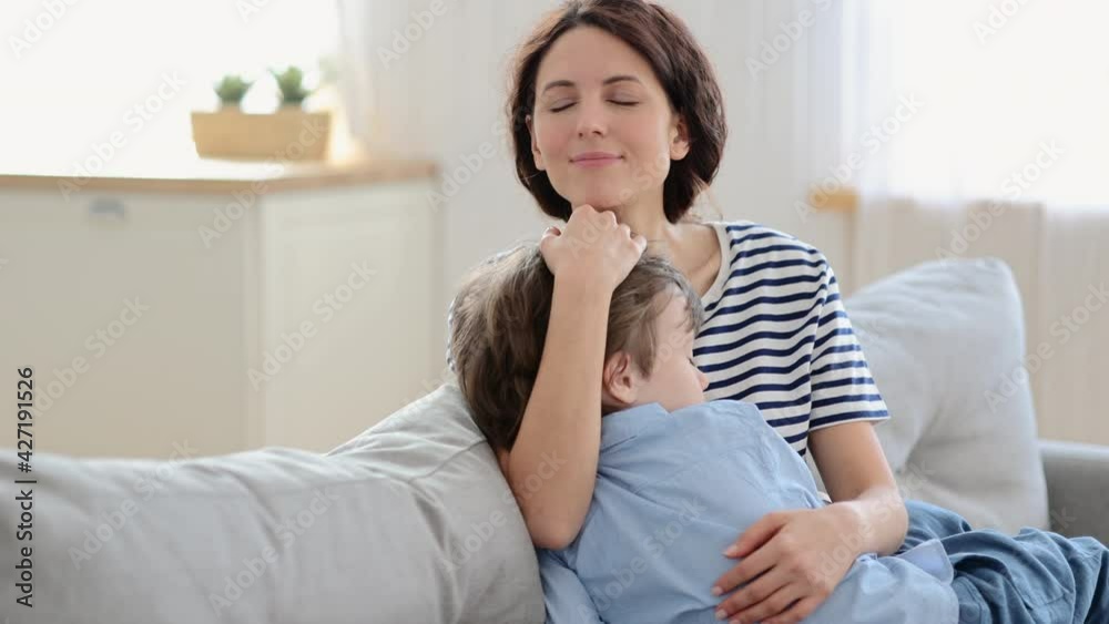 Happy mother hug son sleeping on her knees. Cute caucasian mom and preschool kid cuddle on couch at home, spend weekend together. Young mum with little boy. Tender family relationship, care and love Happy mother hug son sleeping on her knees. Cute caucasian mom and preschool kid cuddle on couch at home, spend weekend together. Young mum with little boy. Tender family relationship, care and love