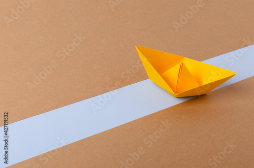 Yellow paper ship on the blue way.Abstract idea of blocked Suez Canal photo